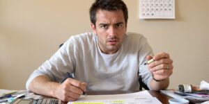 personne tenant un stylo et une calculatrice, regardant un formulaire fiscal avec une expression confuse