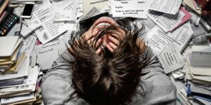 Personne se tenant la tête devant des papiers